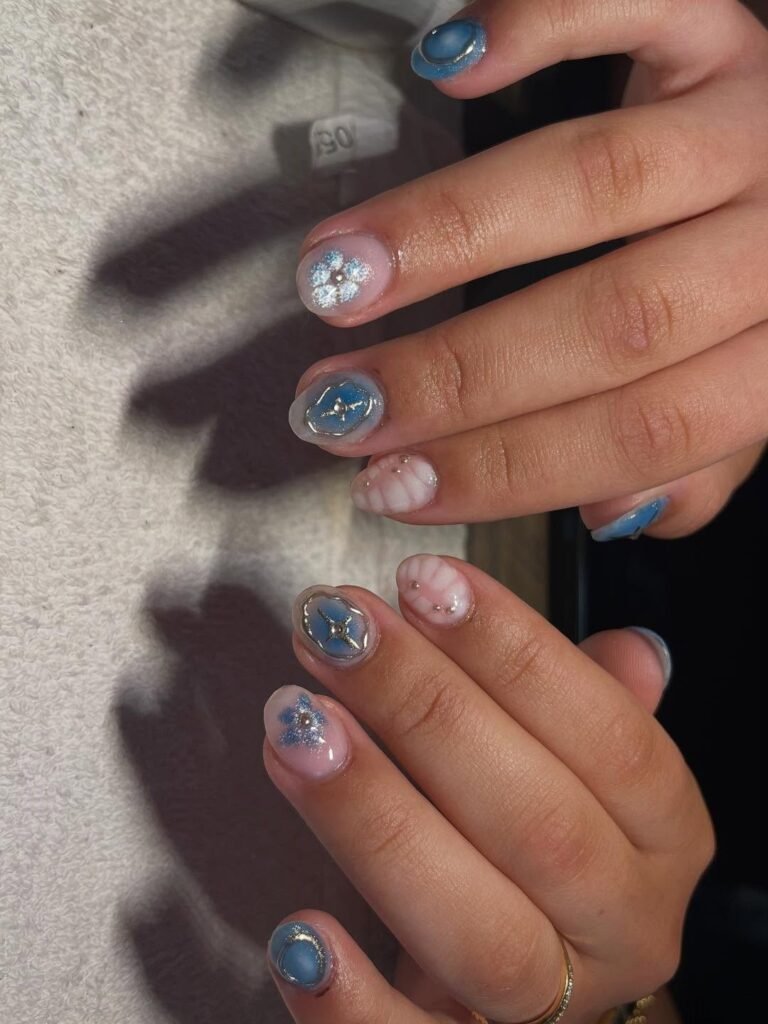 Soft blue-pink pearl and glitter gel nail ideas for short nails with floral and star accents.