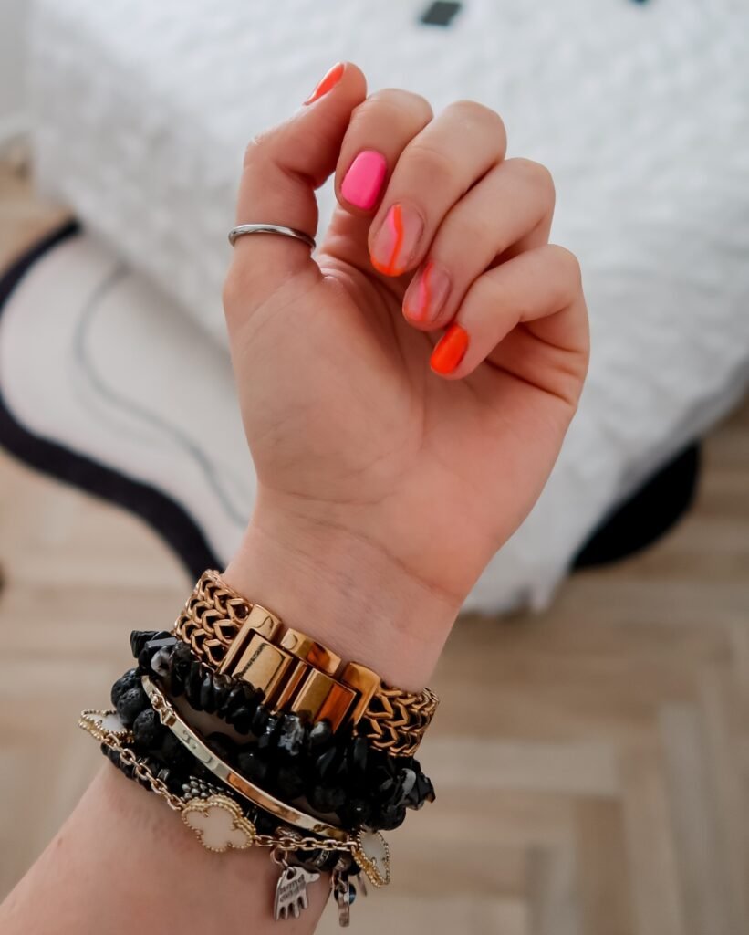 Neon orange to pink ombre gel nail ideas for short nails with bracelet styling.