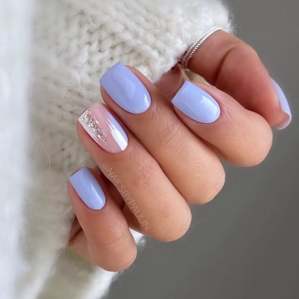 A hand showcasing simple short nail ideas in pastel blue with a glitter accent on one nail for an elegant touch.