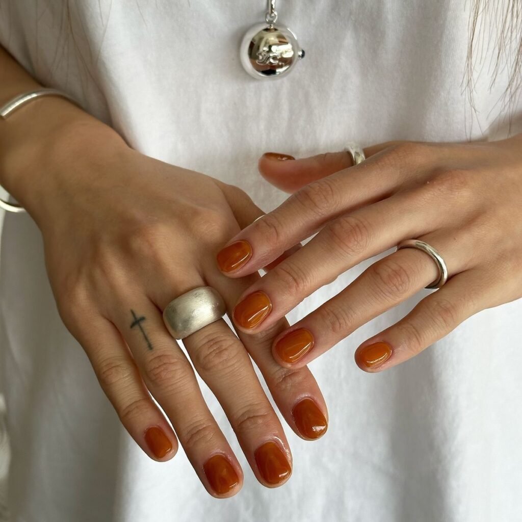 Cozy terracotta orange short round nails ideas styled with silver jewelry for a seasonal touch.