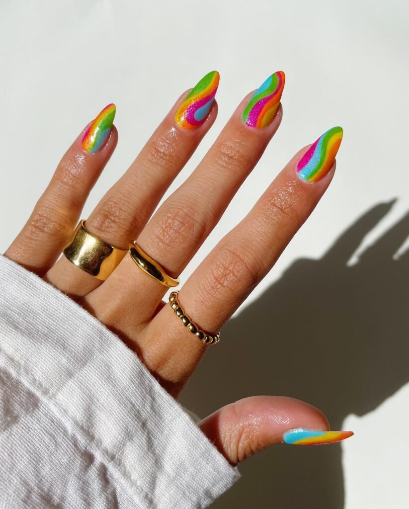 Dynamic concert nails ideas highlighting swirling rainbow waves in bold red, green, and blue shades for a striking, music festival-ready nail design.