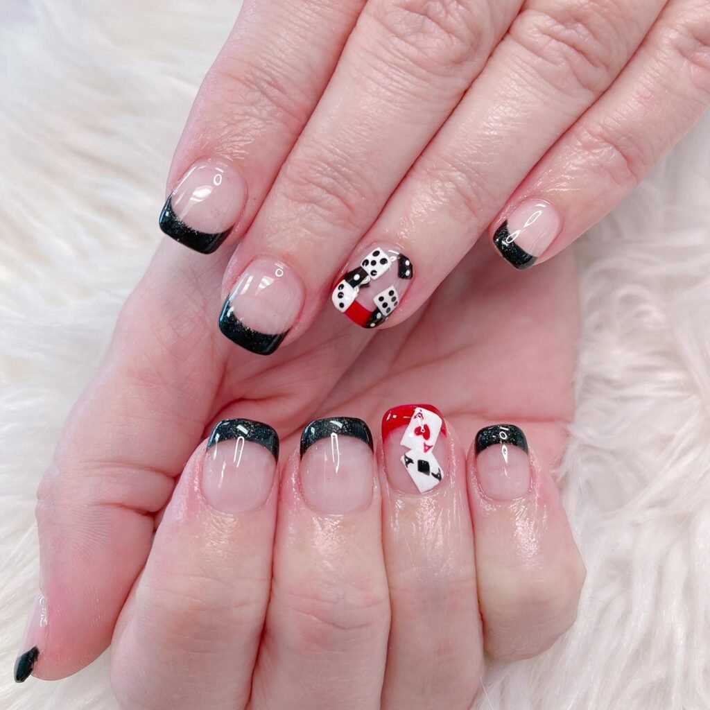 Elegant vegas nails ideas showcasing black French tips accented with dice and ace of hearts motifs for a casino-inspired look.