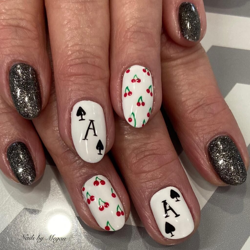 Chic vegas nails ideas with white bases dotted by cherries and ace of spades alongside sparkling silver accents.
