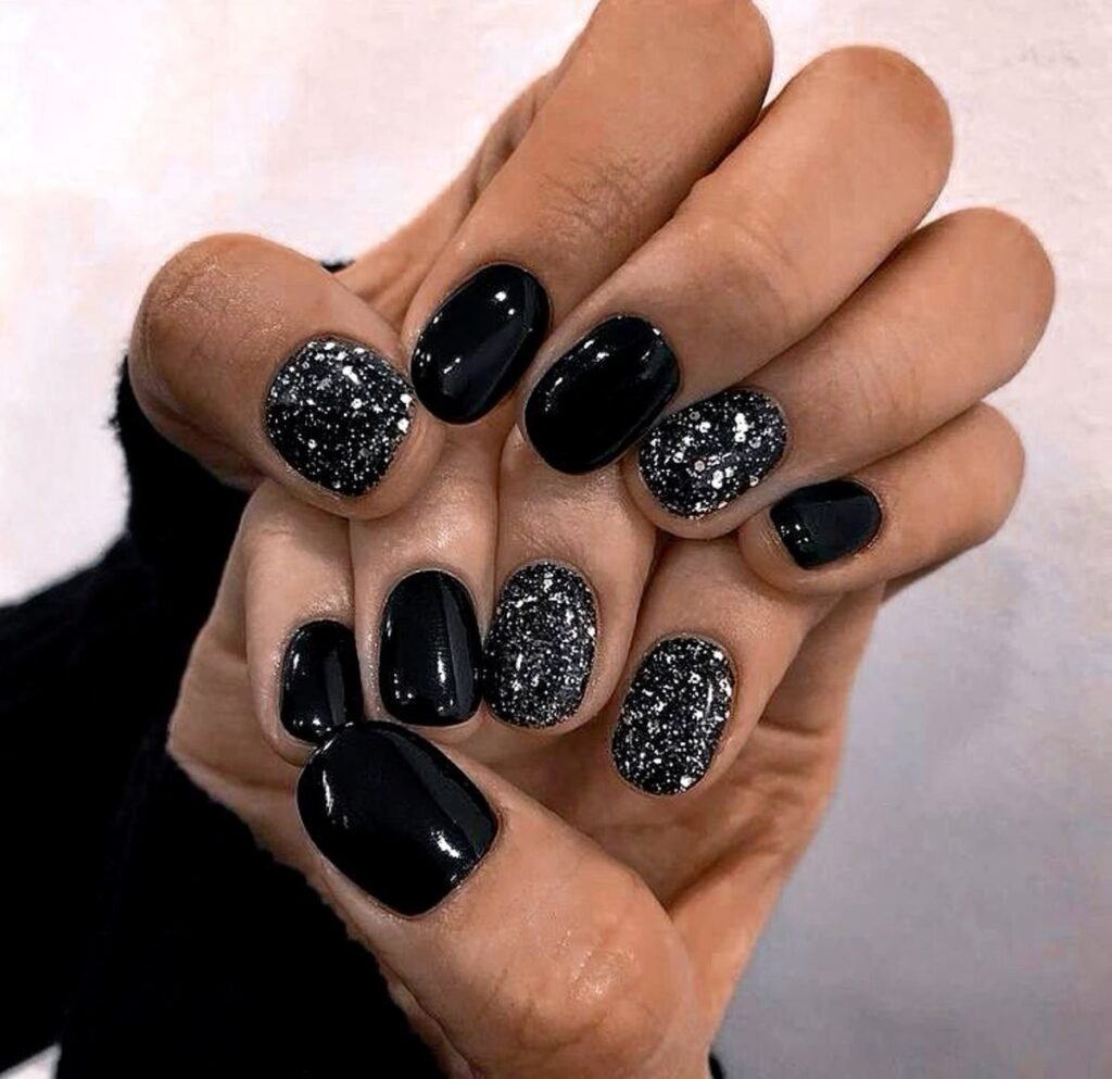 Hands displaying black nails with silver glitter accents, embodying sparkling short black nails ideas ideal for evening outings or festive occasions.