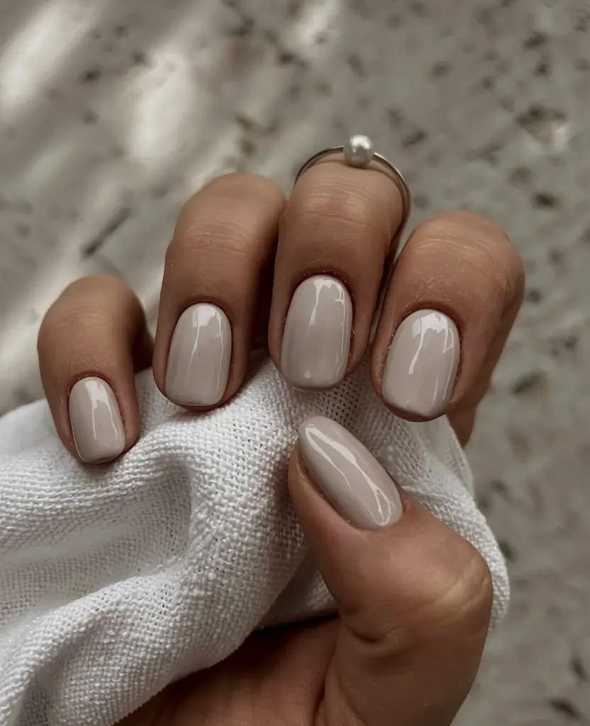 Chic nude short nails ideas in beige tones, paired with a pearl ring for everyday elegance.