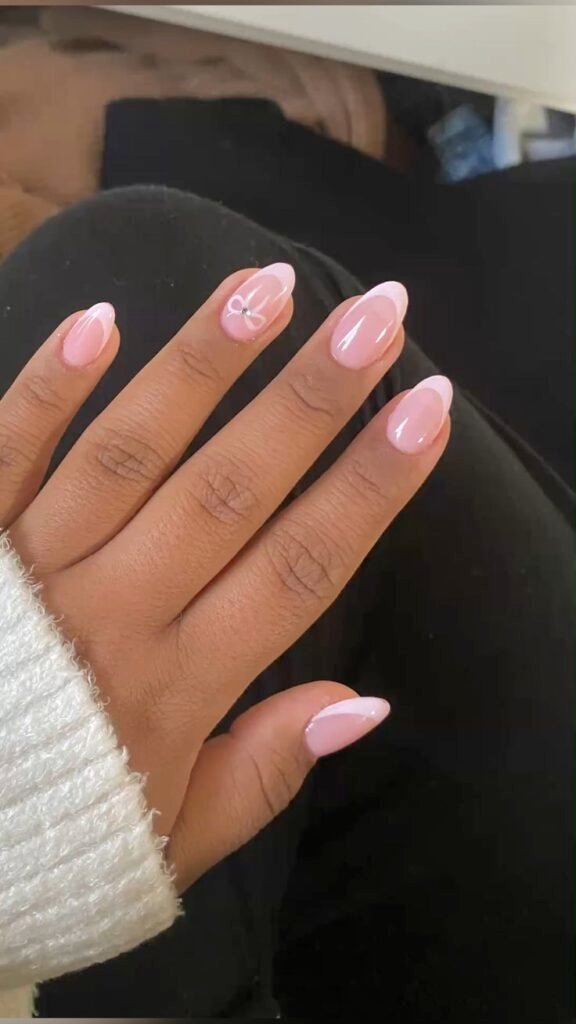Elegant Pink Short Nails Ideas incorporating French tips and a dainty bow accent.