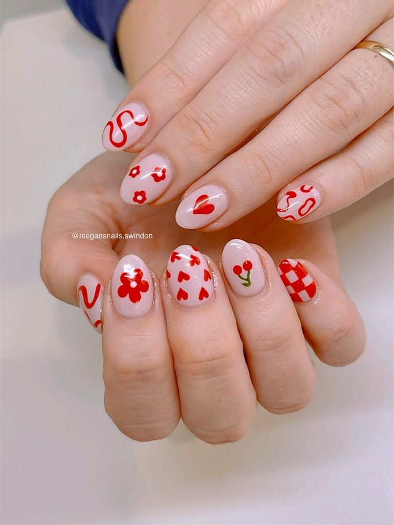 Creative short red nails ideas on hands with oval nails using a light pink base decorated with assorted red motifs like flowers, hearts, cherries, checkers, and wavy lines.