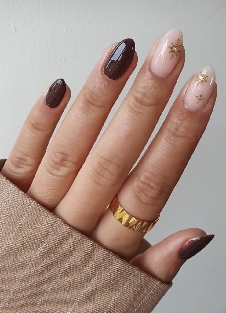 Celestial short brown nails ideas combining dark brown polish with pink bases and gold star embellishments for a dreamy effect.