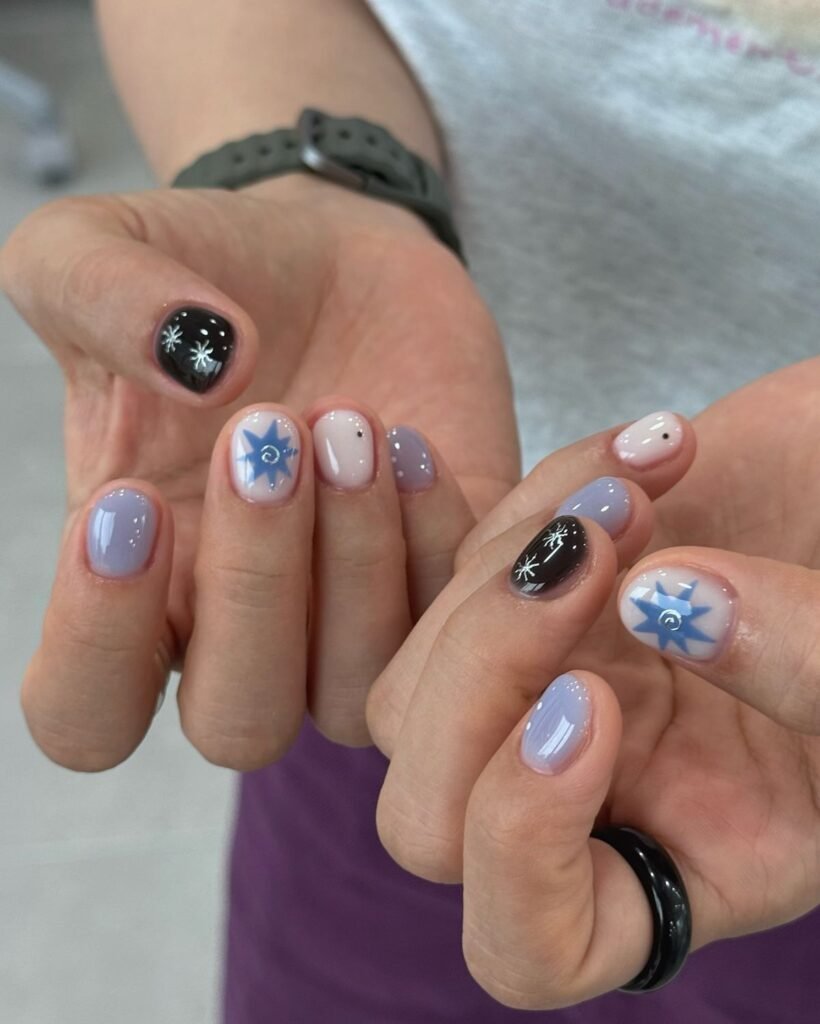 Mystical blue and black nails with star motifs as short nail ideas for summer evenings under the stars.