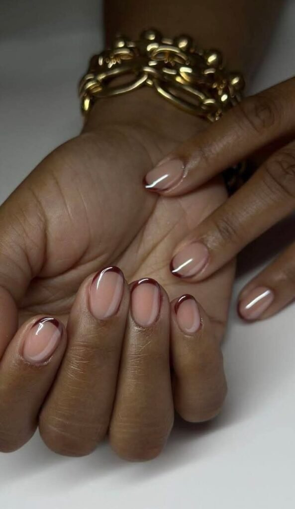 This photo features elegant short round nails ideas with a nude base and subtle brown French tips for a chic, minimalist look.