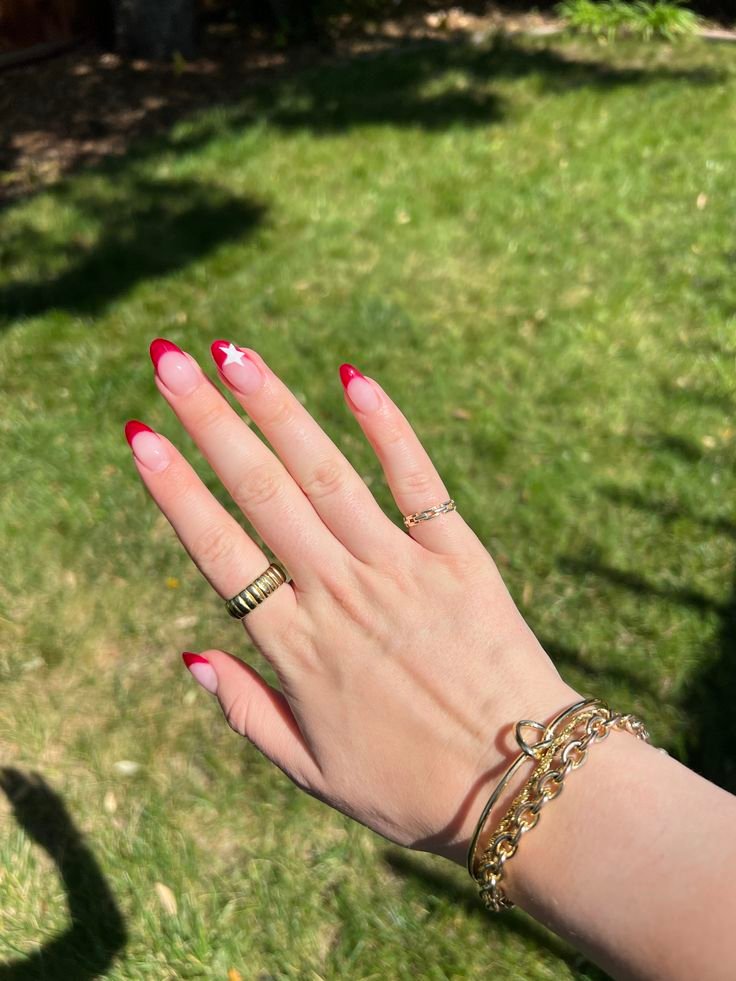 Stylish red French tip concert nails ideas featuring a white star accent on almond-shaped nails for a fun and festive look