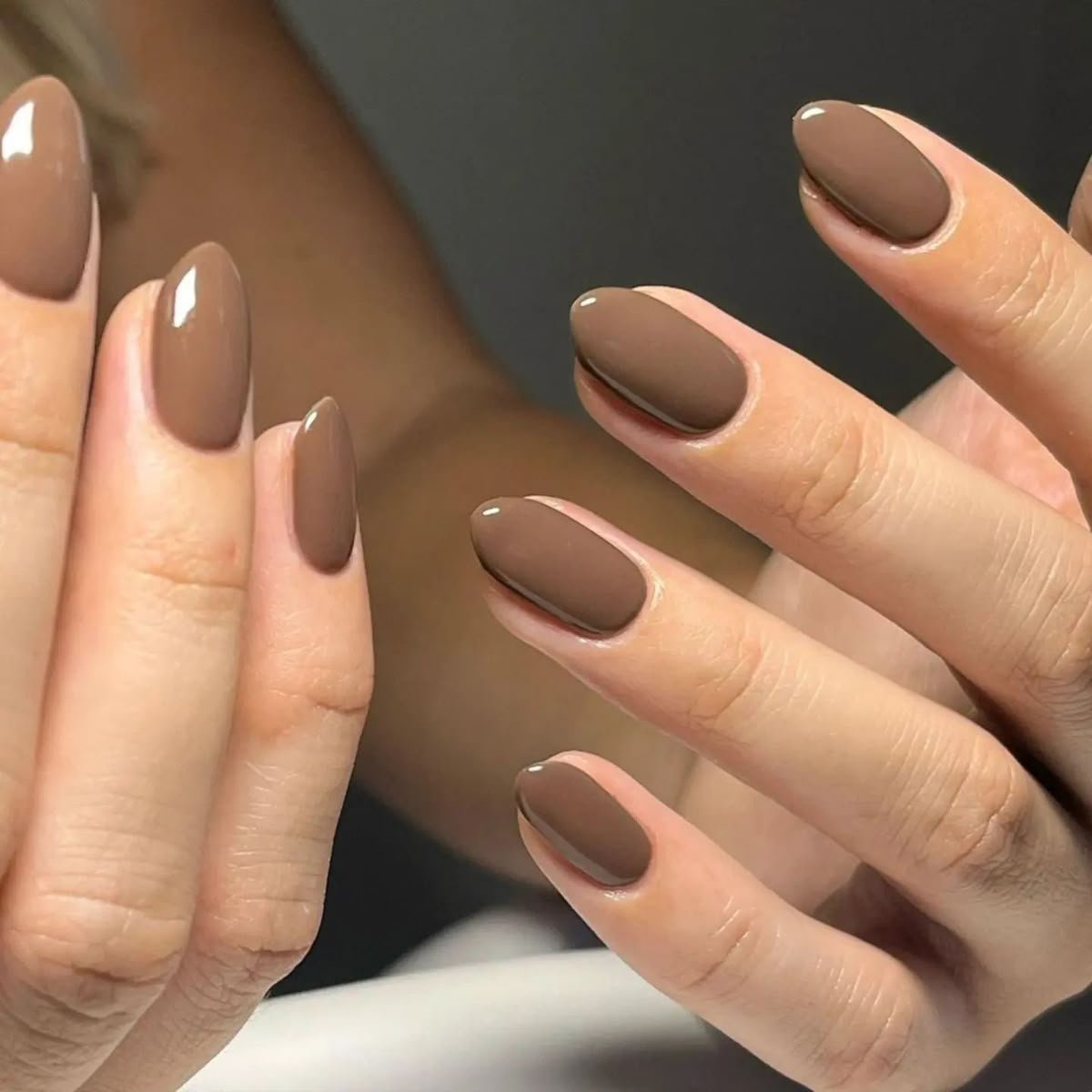 Hand featuring short brown nails ideas with glossy warm brown almond-shaped nails, showcasing a chic and versatile manicure style for everyday elegance.