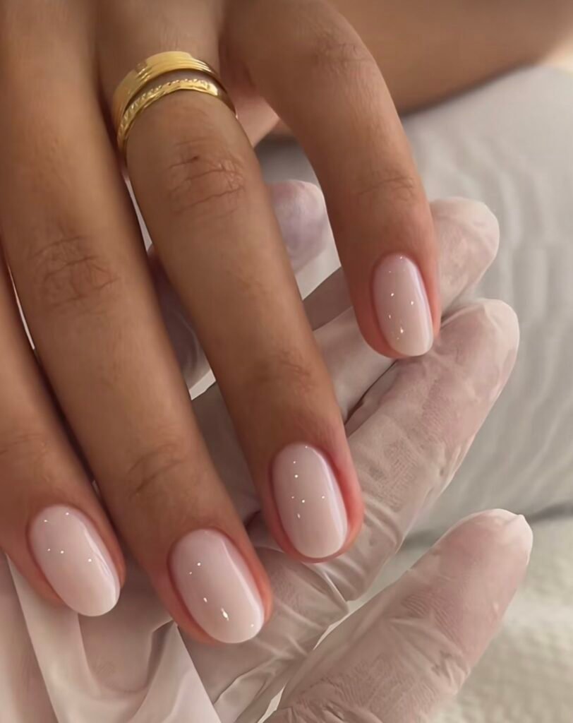 Sparkling nude short nails ideas incorporating glitter for a subtle glamorous vibe with gold accessories.