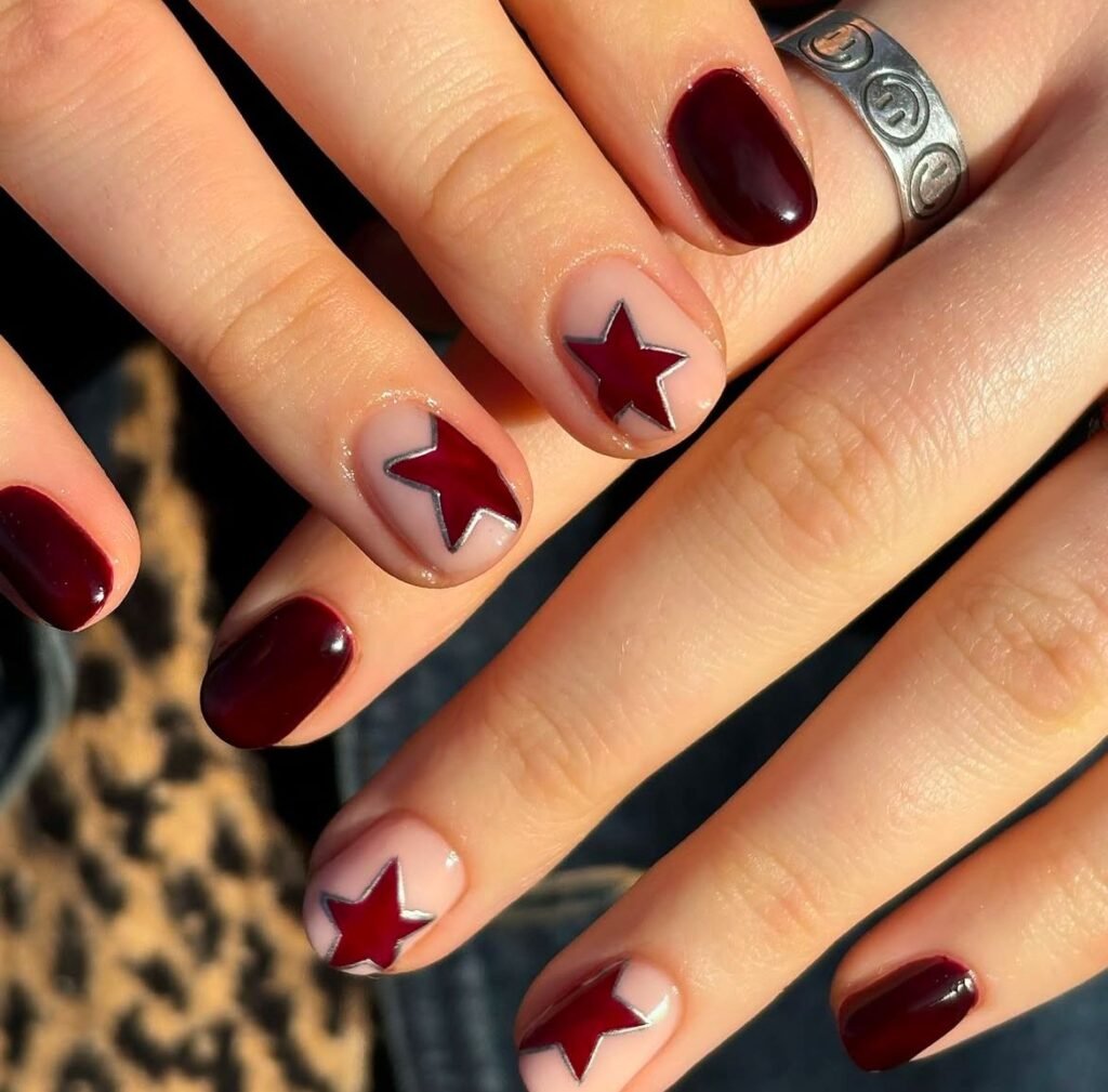 Striking short brown nails ideas with burgundy bases and red star accents outlined in silver for an edgy, star-themed manicure.