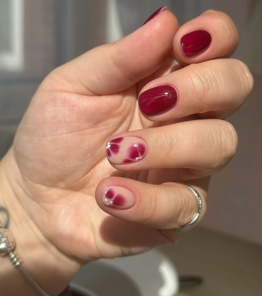 Vibrant short spring nails ideas blending deep red with marbled pink patterns.