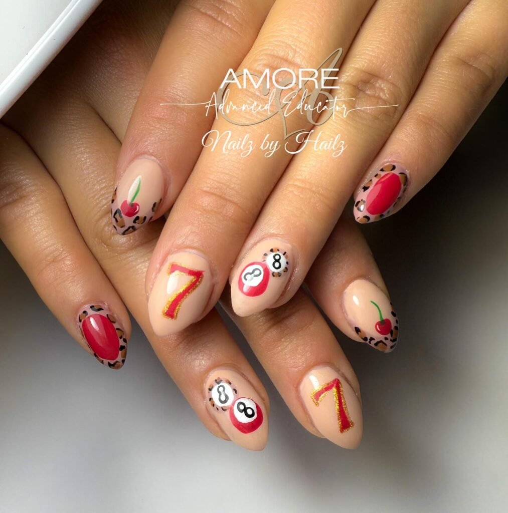 Stylish Vegas nails ideas incorporating lucky 7s, 8-balls, cherries, and leopard patterns in nude and red tones.