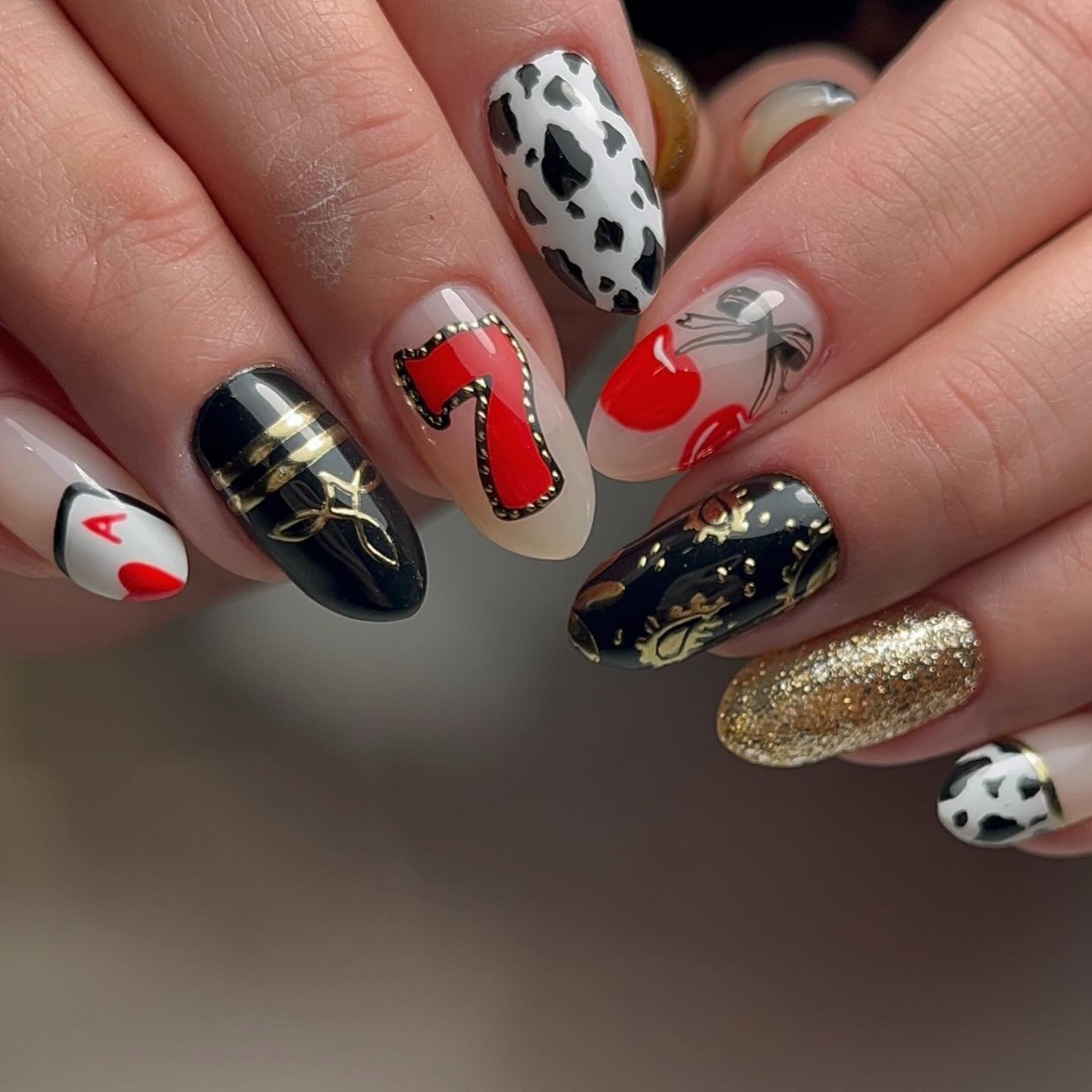 Creative Vegas nails ideas showcasing casino motifs like lucky sevens, cherries, and ace cards in bold red, black, and gold tones for a glamorous manicure.