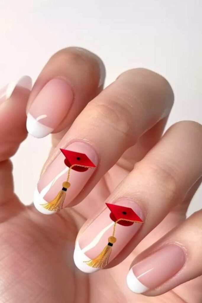 Charming graduation nails ideas with classic French manicure tips and adorable red graduation caps accented by gold tassels.