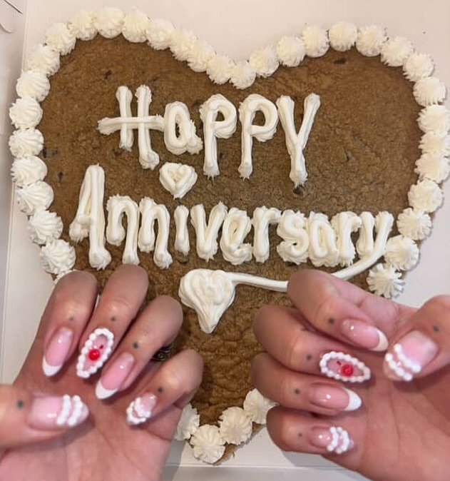 Playful anniversary nails ideas with white French tips and cherry decorations, perfectly complementing a "Happy Anniversary" cookie cake celebration.
