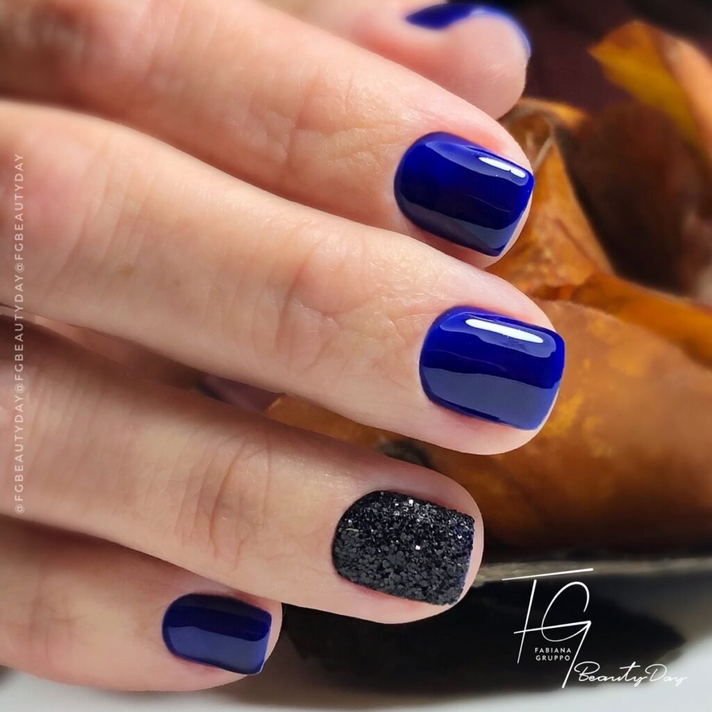 Elegant blue short nails ideas featuring deep navy polish and a bold black glitter accent for a sophisticated look.