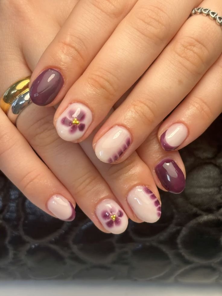 Whimsical short spring nails ideas with violet flowers and purple accents blooming on a soft base.