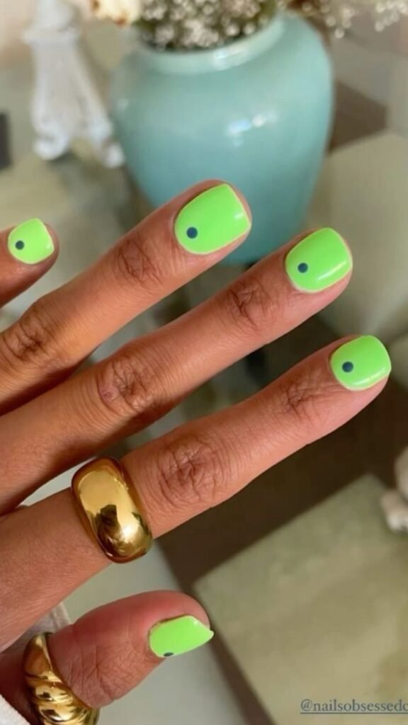 Bright neon green nails with black dots as short nail ideas for summer, adding a pop of color to any outfit.