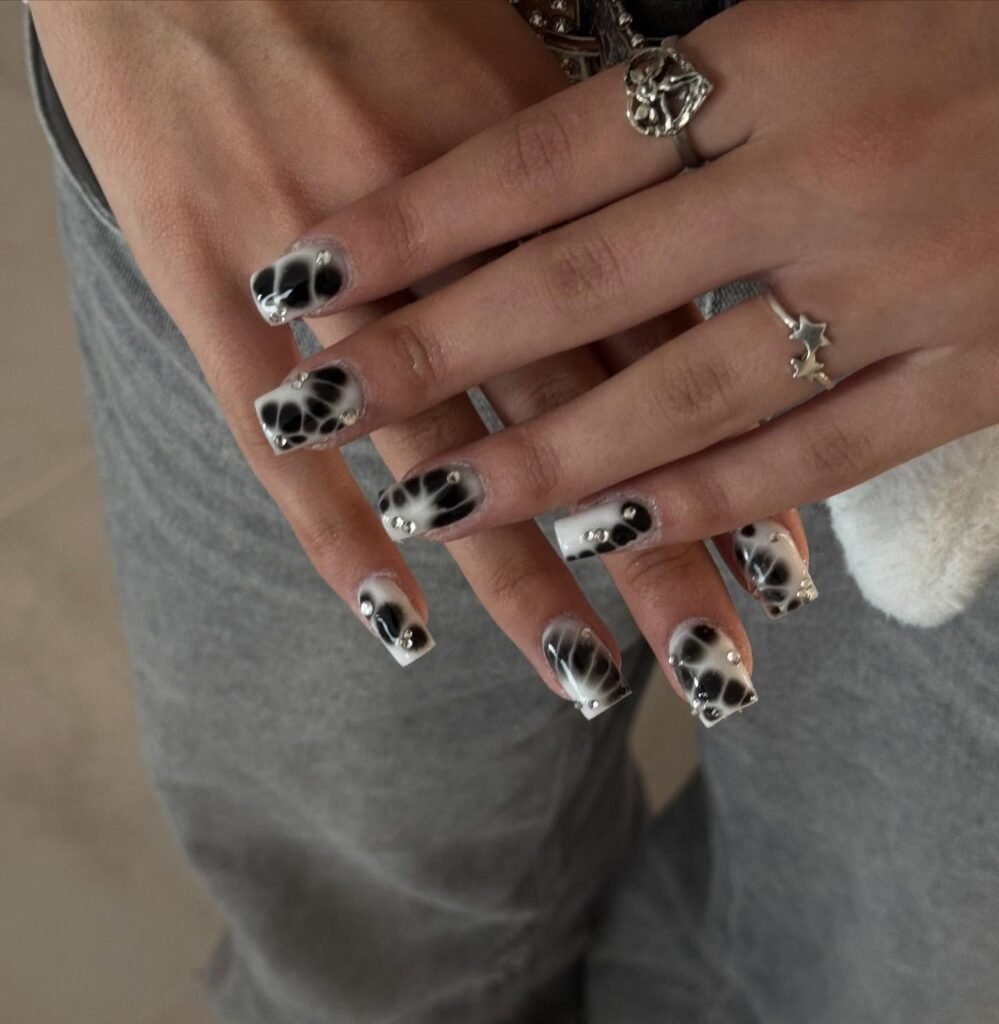 Bold black and white marbled patterns with studs as short square nails ideas for an edgy vibe.