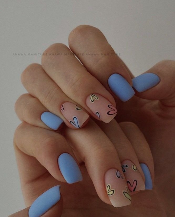 Delightful anniversary nails ideas showcasing alternating pastel blue and nude shades with colorful outlined heart designs for a romantic touch.