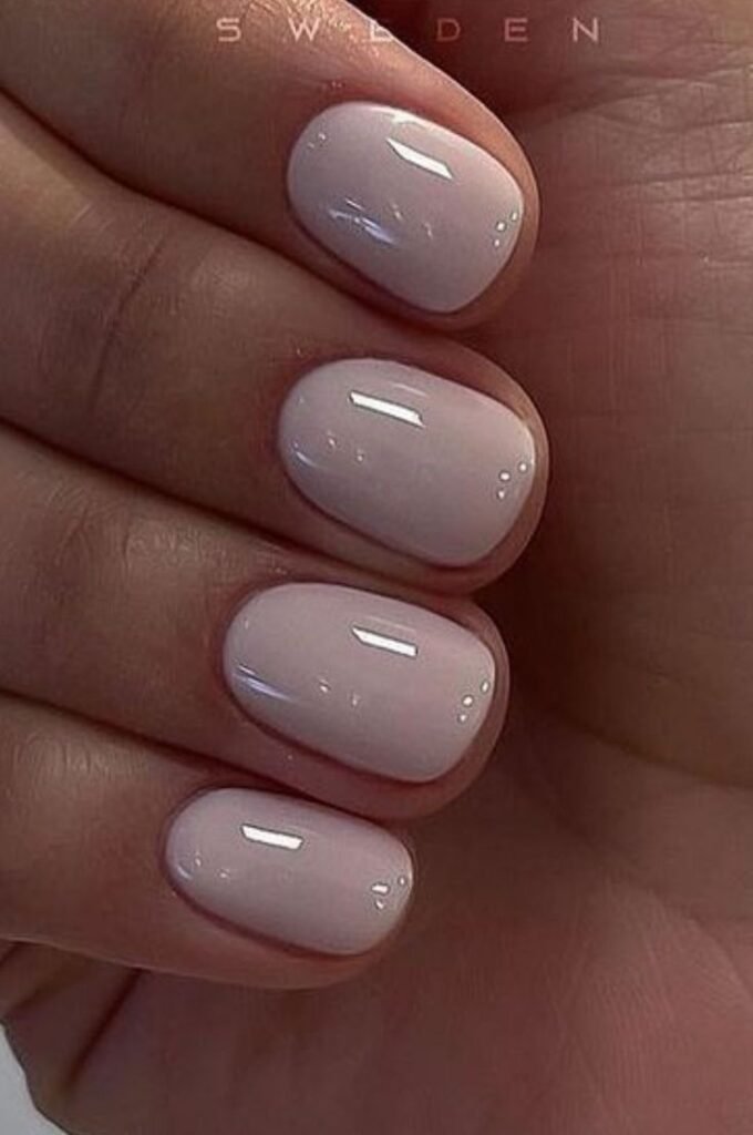 Minimalist nude short nails ideas with glossy pink hues, inspired by Swedish manicure trends.