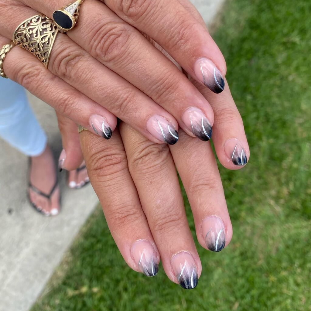 Check out modern short almond nails ideas featuring a smooth gradient ombre from soft nude at the base to deep black at the tips, enhanced with delicate thin white wavy lines for an abstract and edgy contemporary manicure style.