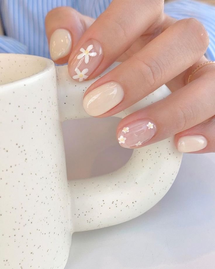 Fresh short spring nails ideas featuring dainty white daisies on a natural sheer base, perfect for everyday elegance.