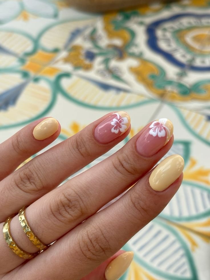 Sunny yellow and pink nails featuring white flowers as short nail ideas for summer, ideal for beach vacations.