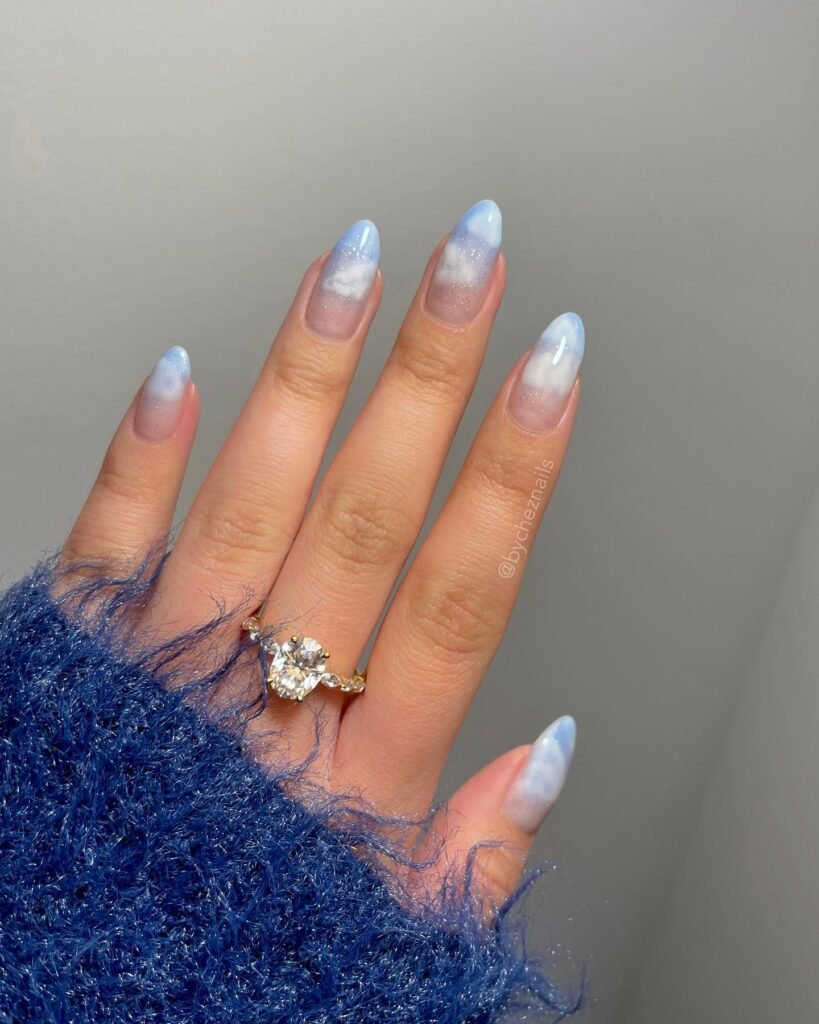 Whimsical anniversary nails ideas featuring blue gradient with cloudy designs and sparkles for a dreamy vibe.