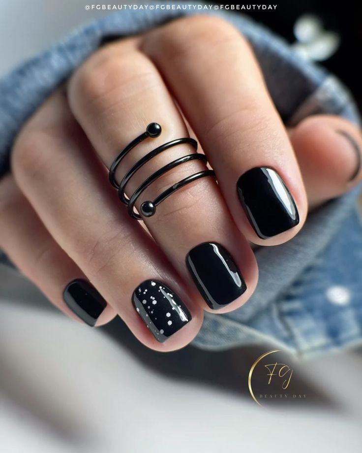 Elegant black short nails ideas with a starry pattern on glossy polish, complemented by a spiral ring for a cosmic vibe.