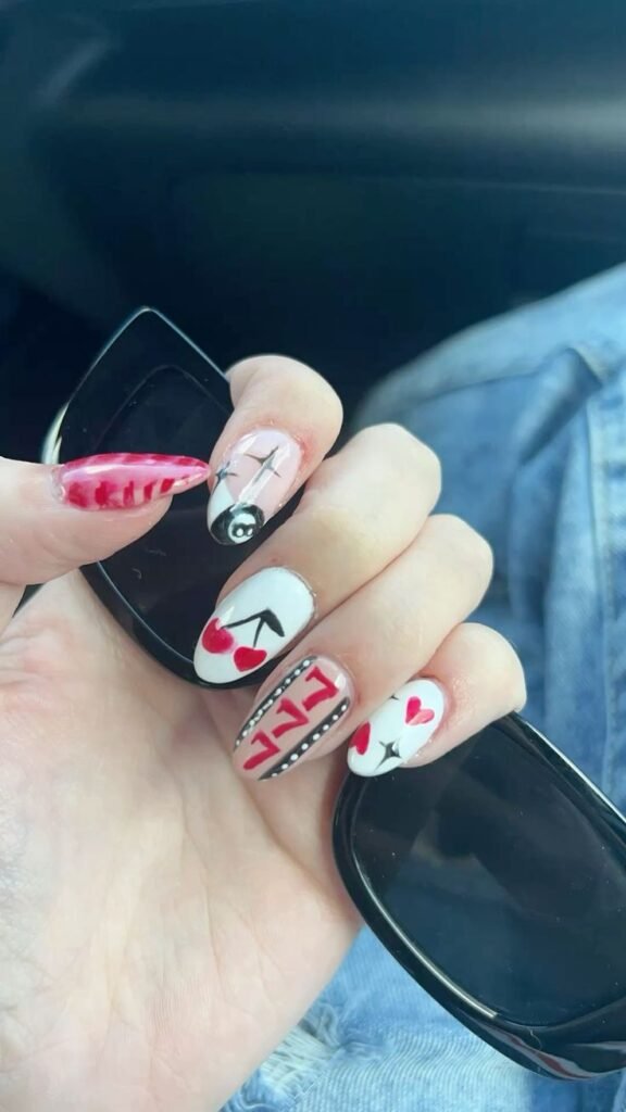 Stylish concert nails ideas featuring cherries, an 8-ball, hearts, and striped patterns in red, pink, and black for a fun rock vibe.