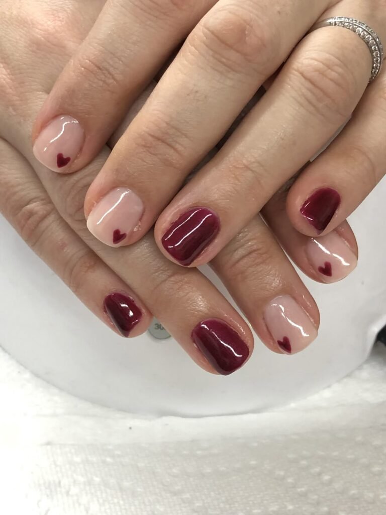 Playful short brown nails ideas blending nude tones with heart details and deep red accents for a cute twist.