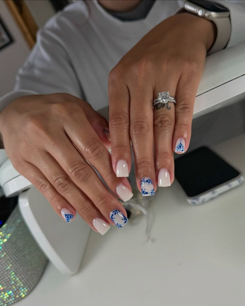 Elegant hands with blue floral patterns on pale pink short square nails ideas inspired by classic porcelain art.