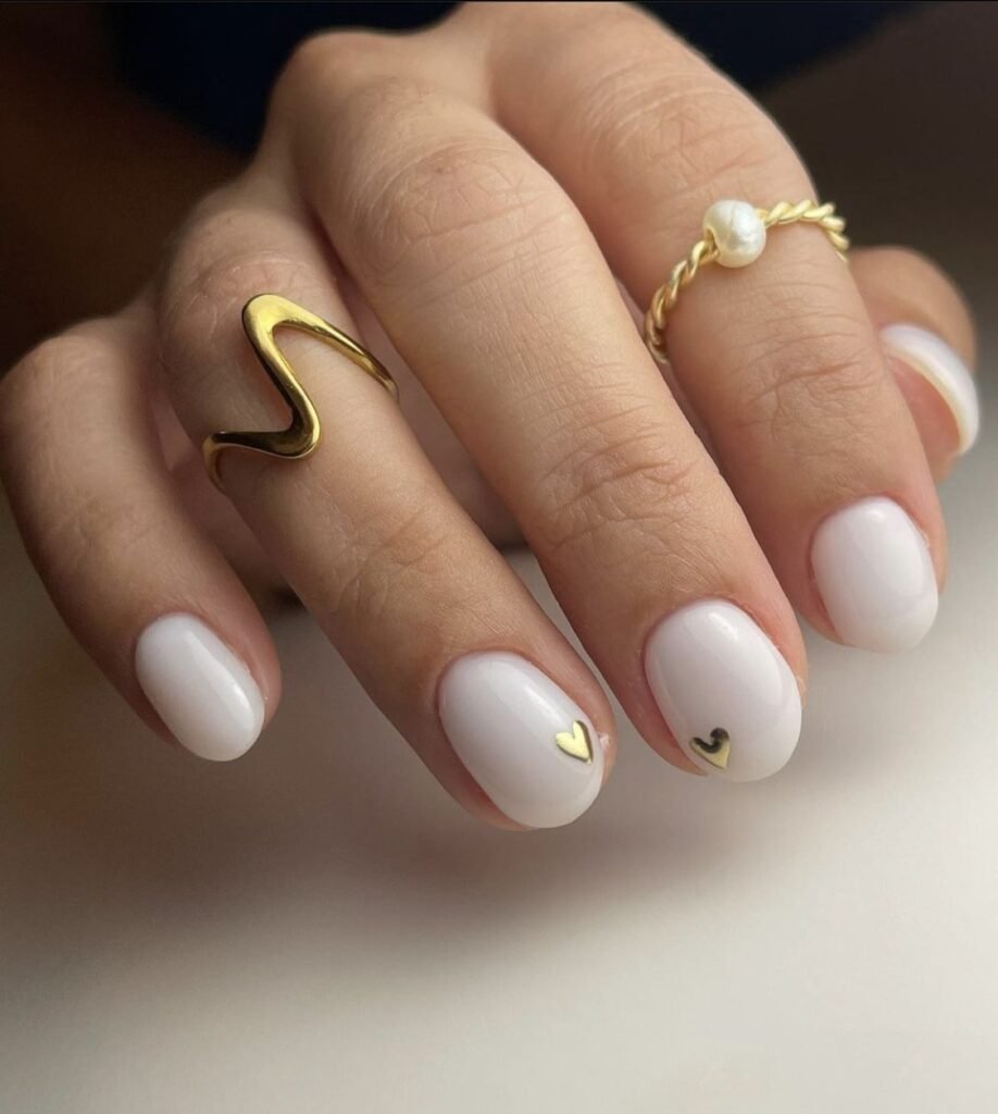 Charming white short nails ideas featuring a subtle gold heart detail for a romantic touch.