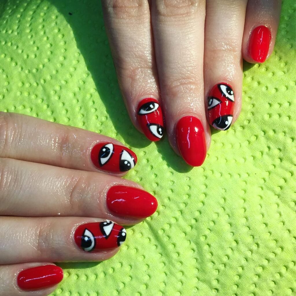 Creative red short nails ideas featuring whimsical eye patterns in bold contrasts.