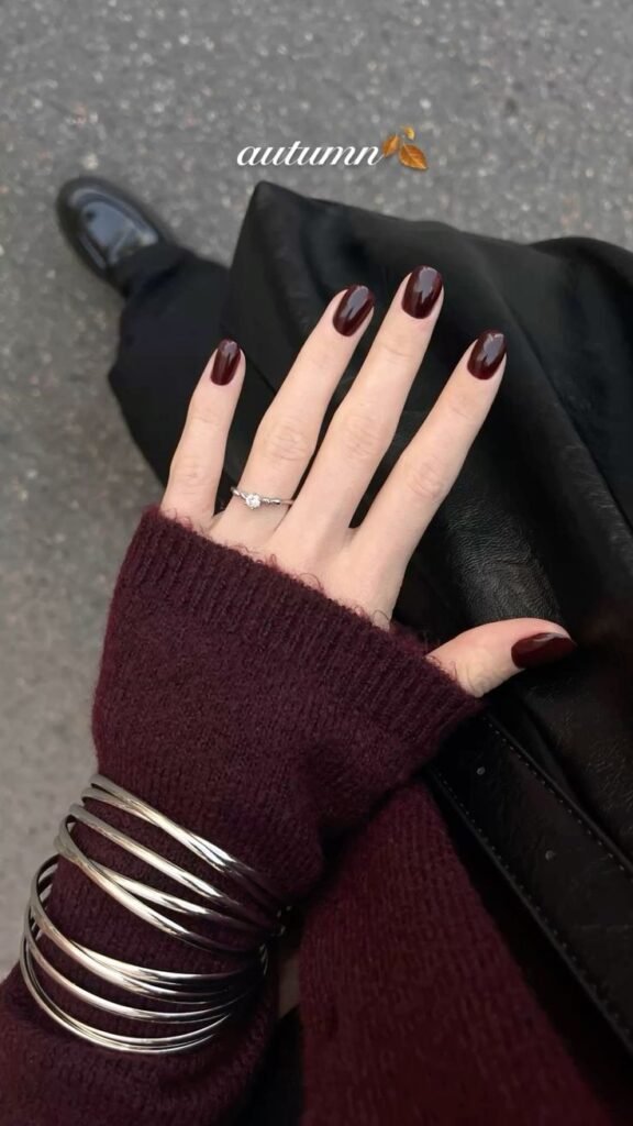 Cozy short brown nails ideas in deep burgundy hues, perfect for autumn accessorized with silver jewelry.