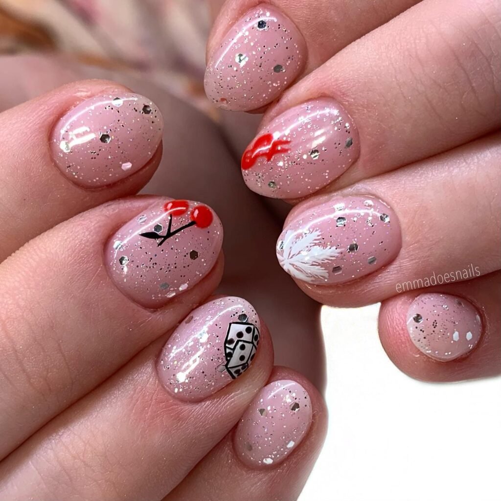 Glamorous Vegas nails ideas showcasing cherries, dice, and flames on sparkling pink glitter polish.