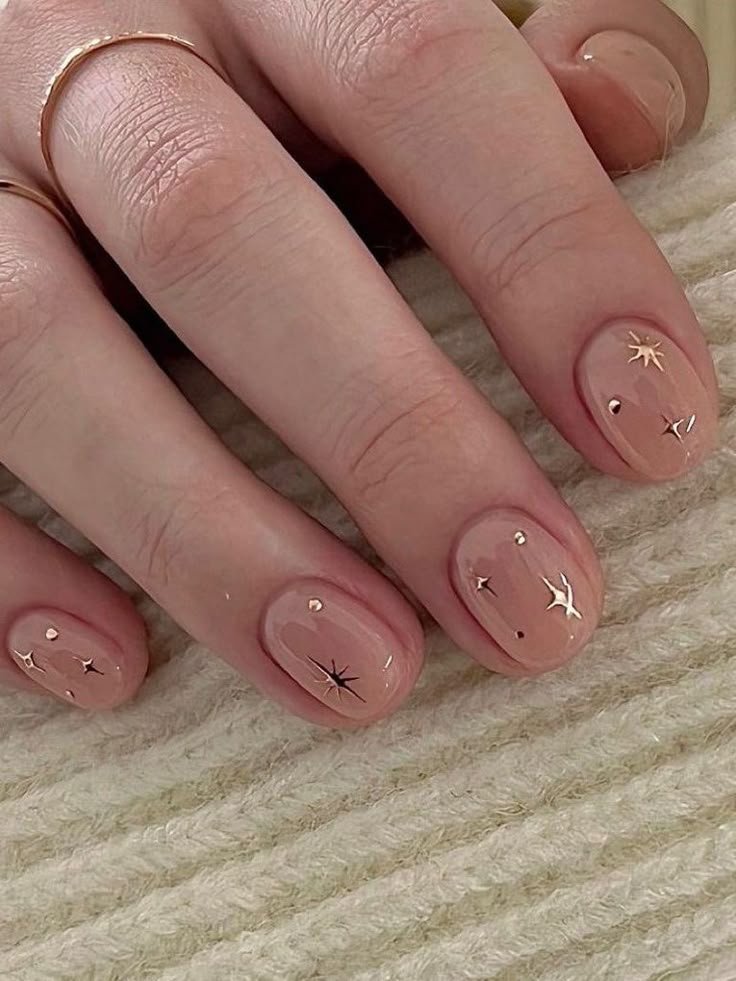Subtle short spring nails ideas using nude polish accented with sparkling gold stars for a sophisticated touch.