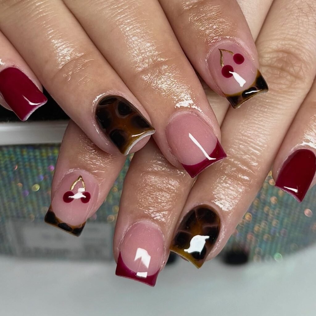 Hands showing mixed designs including cherries and tortoiseshell on short square nails ideas for a fun and playful manicure.
