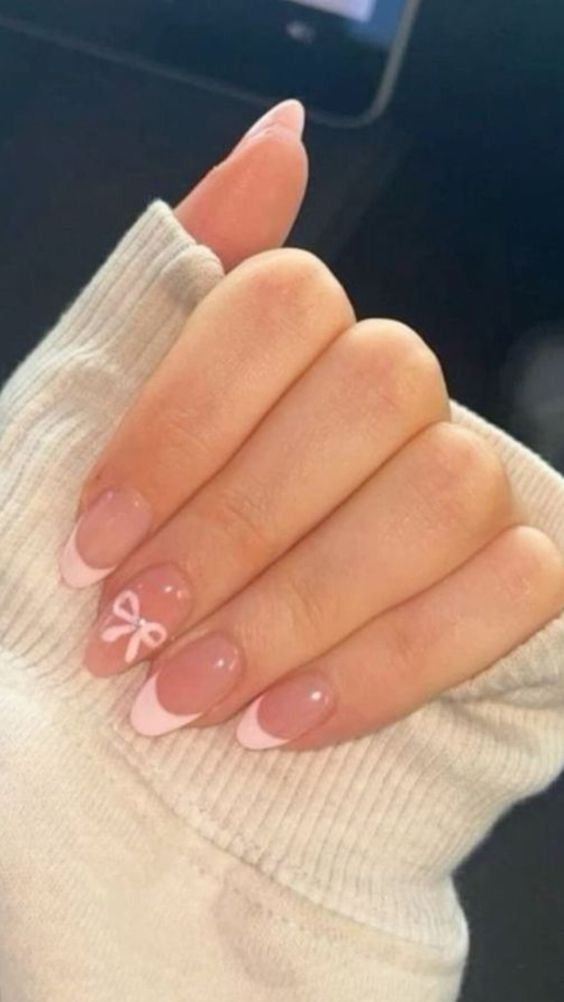 Cute pink nails ideas short featuring French tips and a bow detail on almond-shaped nails for a playful look.