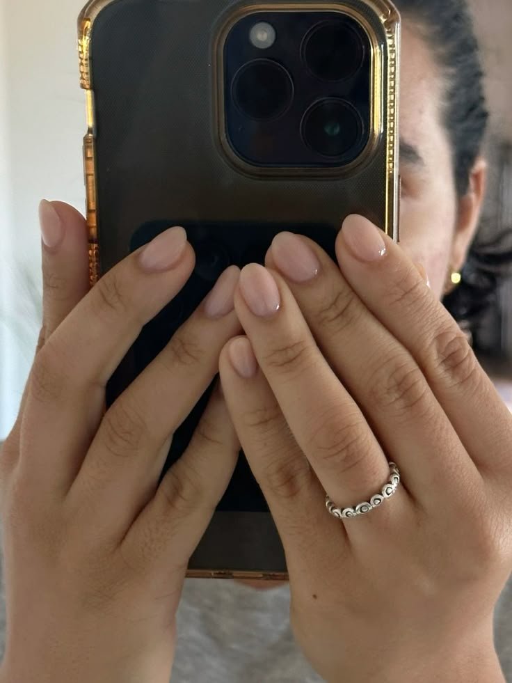 Subtle sheer pink short round nails ideas in a casual selfie style with simple accessories.