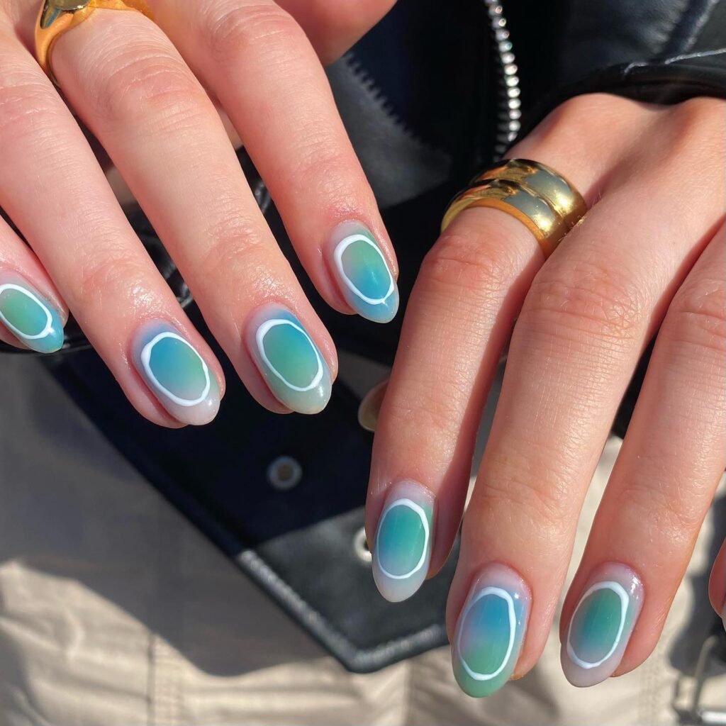 Elegant april nails ideas with turquoise ombré and white oval outlines on perfectly manicured hands.