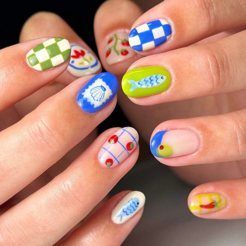 Fun and colorful april nails ideas featuring checkered patterns, strawberries, fish, and playful fruit motifs.