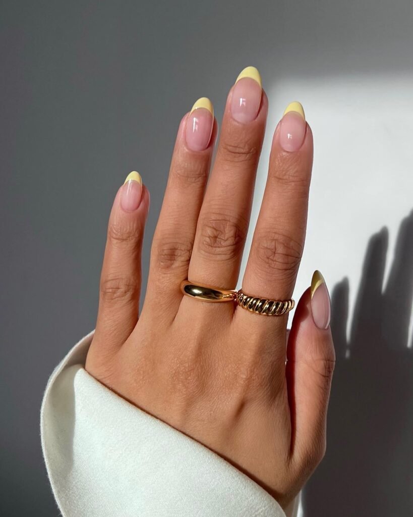 Simple yet stunning april nails ideas with yellow French tips and natural pink bases.