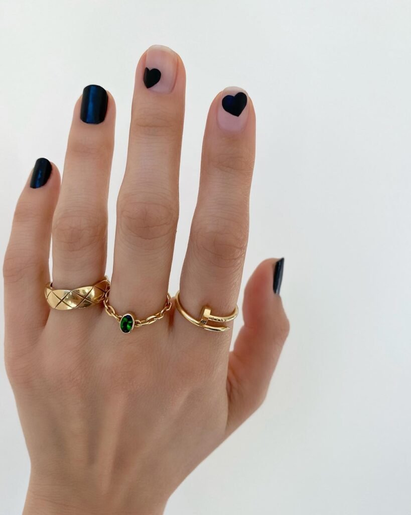 Stunning engagement nails ideas in deep navy blue with subtle black heart details and gold rings.