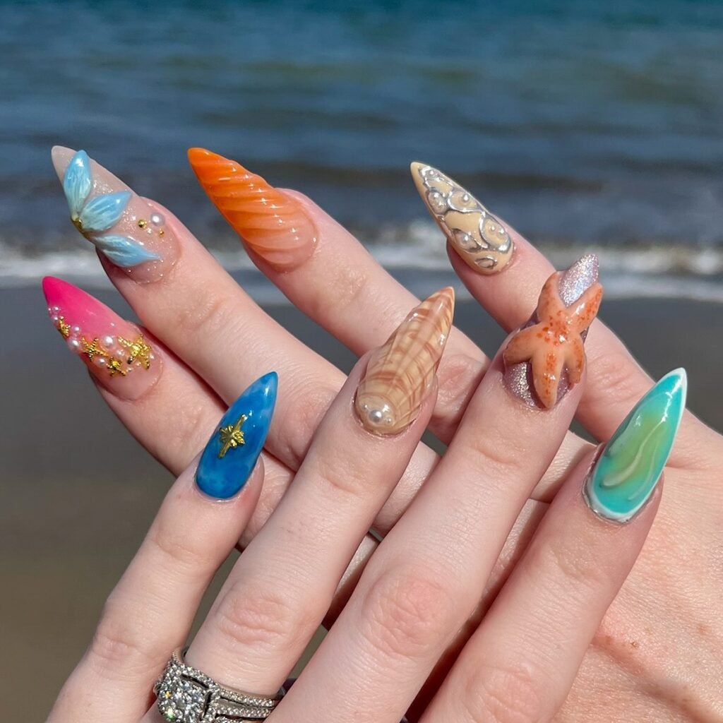 Fun hawaii nails ideas inspired by the beach, including oceanic colors, 3D starfish, shells, and tropical accents on pointed nails against a seaside backdrop.